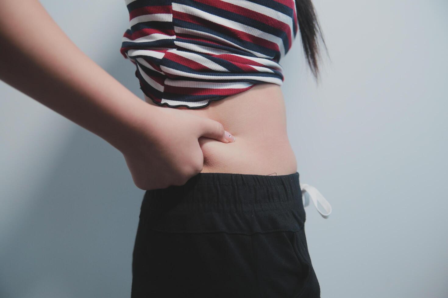 Women body fat belly. Obese woman hand holding excessive belly fat. diet lifestyle concept to reduce belly and shape up healthy stomach muscle. photo