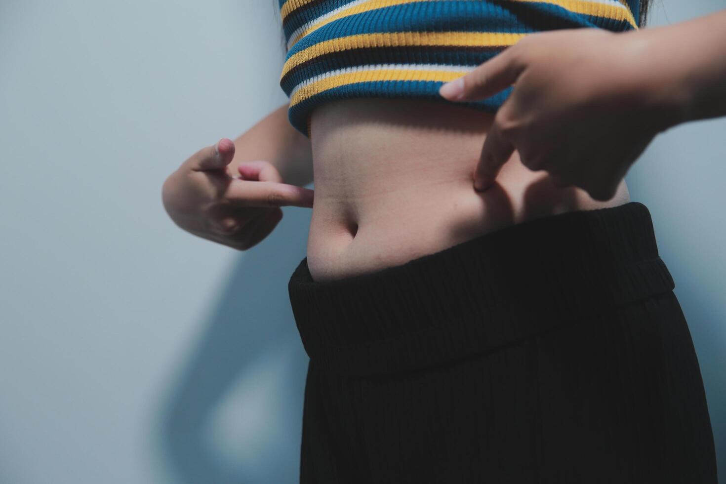 Women body fat belly. Obese woman hand holding excessive belly fat. diet lifestyle concept to reduce belly and shape up healthy stomach muscle. photo