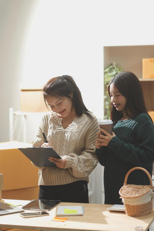Startup small business SME, Entrepreneur owner African woman using smartphone or tablet taking receive and checking online purchase shopping order to preparing pack product box. photo