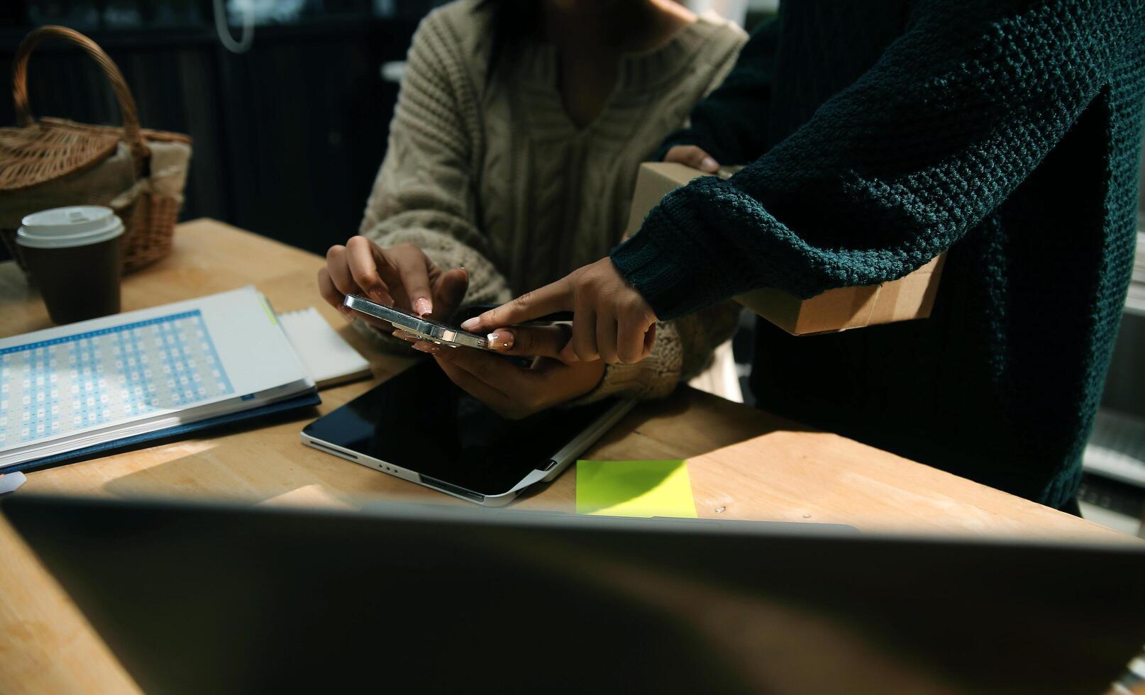 Startup small business SME, Entrepreneur owner African woman using smartphone or tablet taking receive and checking online purchase shopping order to preparing pack product box. photo