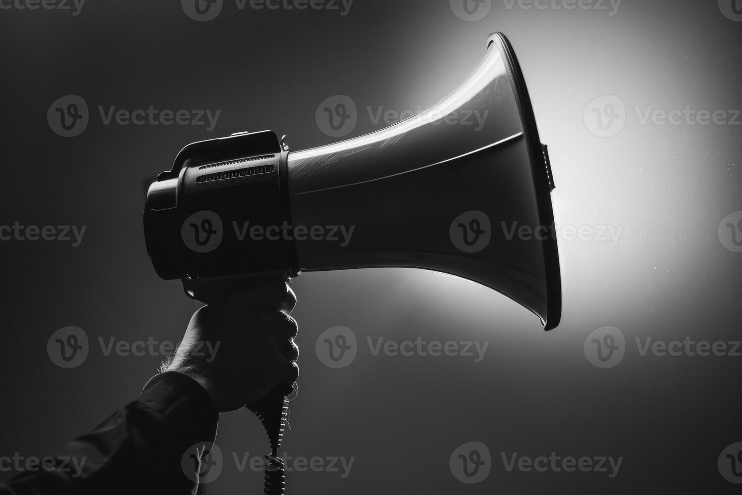 Hand holding a megaphone with bright light in dark background photo