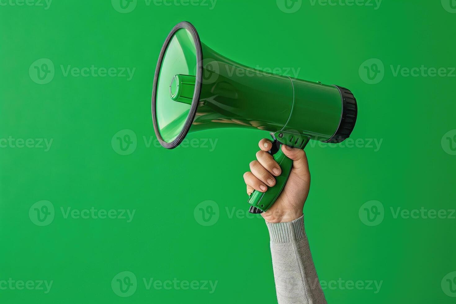 Hand holding a green megaphone on a green background photo