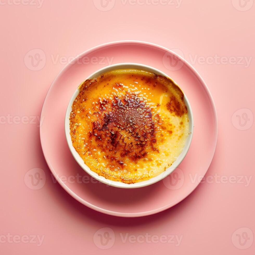 Close up of a creamy Creme Brulee with a perfectly caramelized sugar crust, served on a pink saucer with a pink background. photo