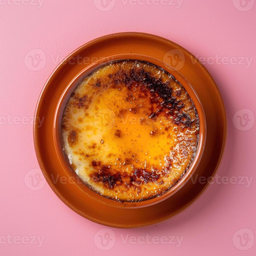Close up of a creamy Creme Brulee with a perfectly caramelized sugar crust, served on a pink saucer with a pink background. photo
