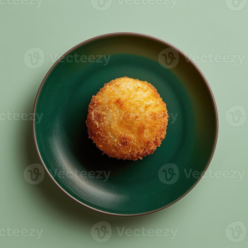 Crispy and golden deep-fried mozzarella ball on a green plate. Delicious appetizer or snack for food blog or restaurant menu. photo
