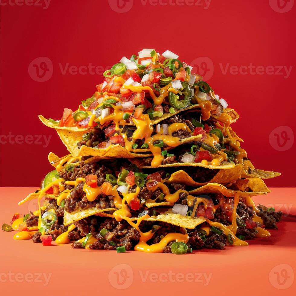 Close-up of a tall stack of loaded nachos, featuring ground beef, cheese, salsa, jalapenos, onions, and sour cream, on a red background. The perfect image for a Mexican restaurant or food blog. photo