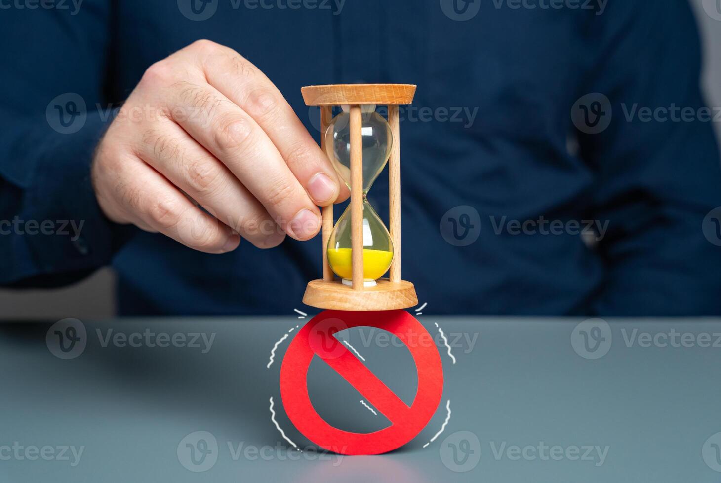 A man crushes a prohibition sign with an hourglass. Concept of lifting prohibitions and restrictions due to expiration of time, irrelevance. Review laws, regulations. Liberalization and legalization. photo