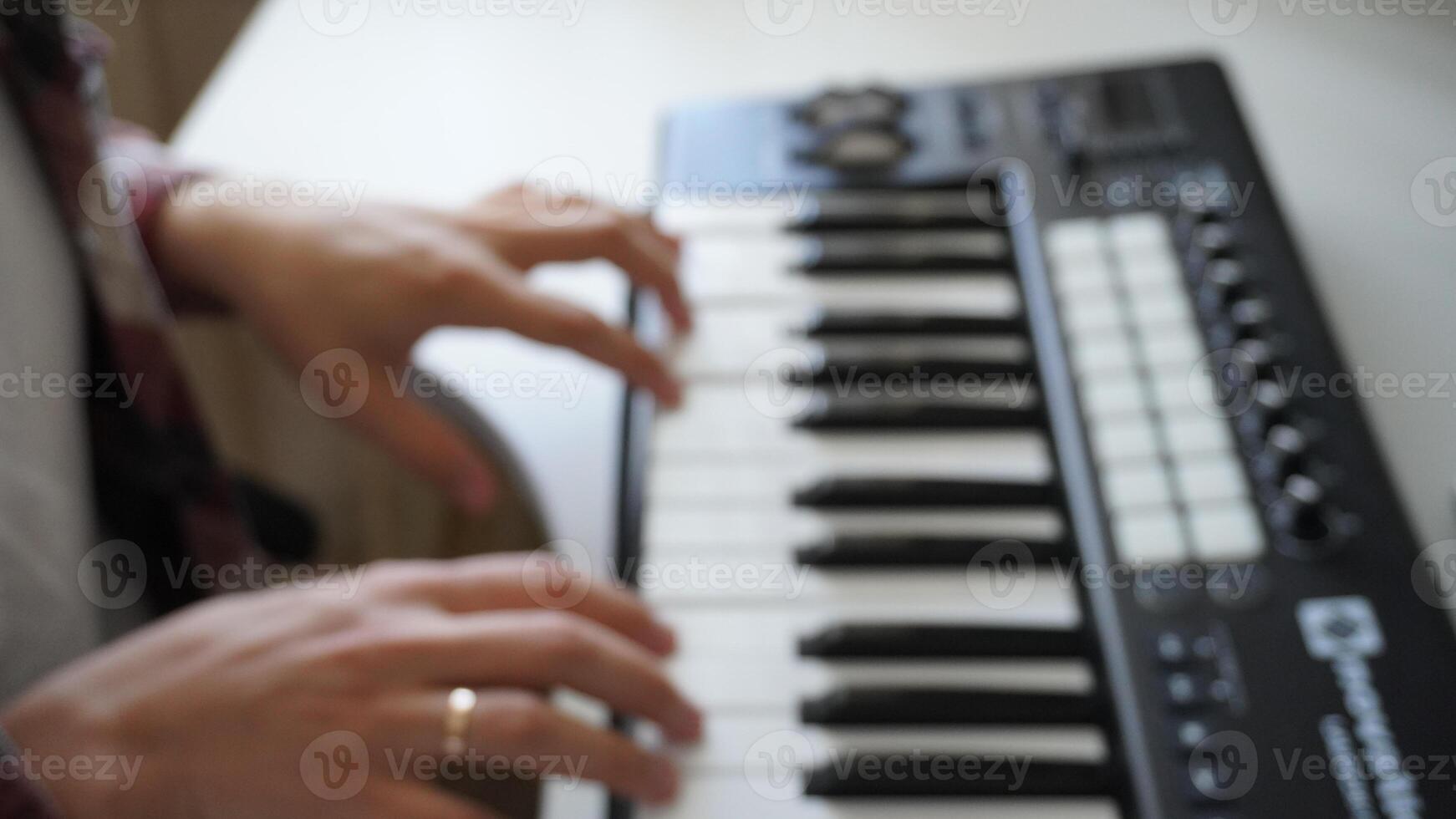 Recording music notes, playing electronic keyboard, midi keys in music sequencer. Hands and midi controller on the table, man composing music, blur photo