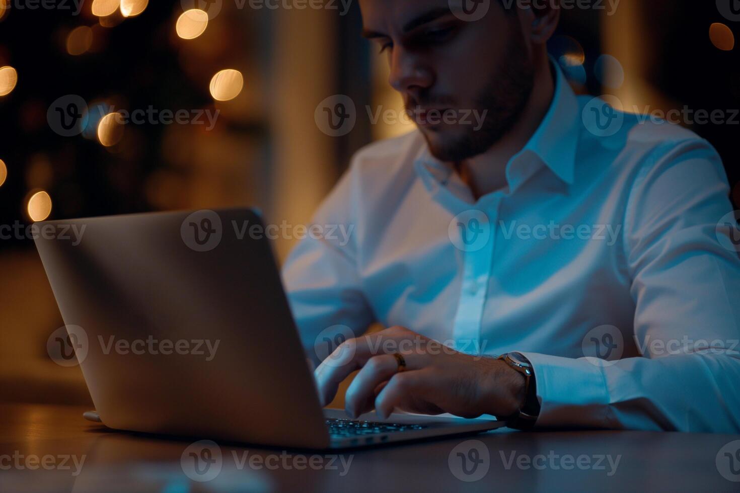 a man in a white shirt is typing on a laptop photo