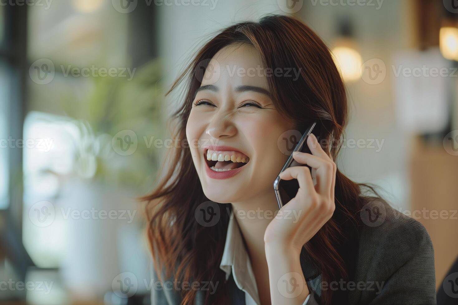 Asian businesswoman talking on smartphone and laughing in her office photo