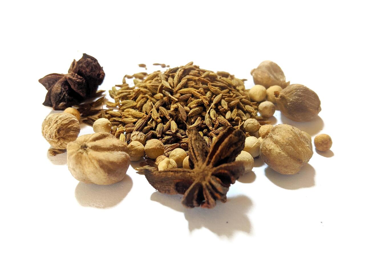 Pile of spices and herbs, there are cumin, cardamom, pepper, and star anise isolated on white photo