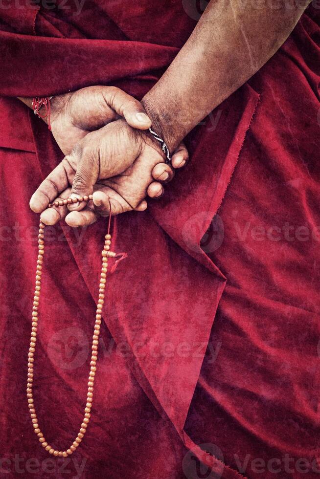 prayer beads in Buddhist monk hands with grunge texture overlaid photo