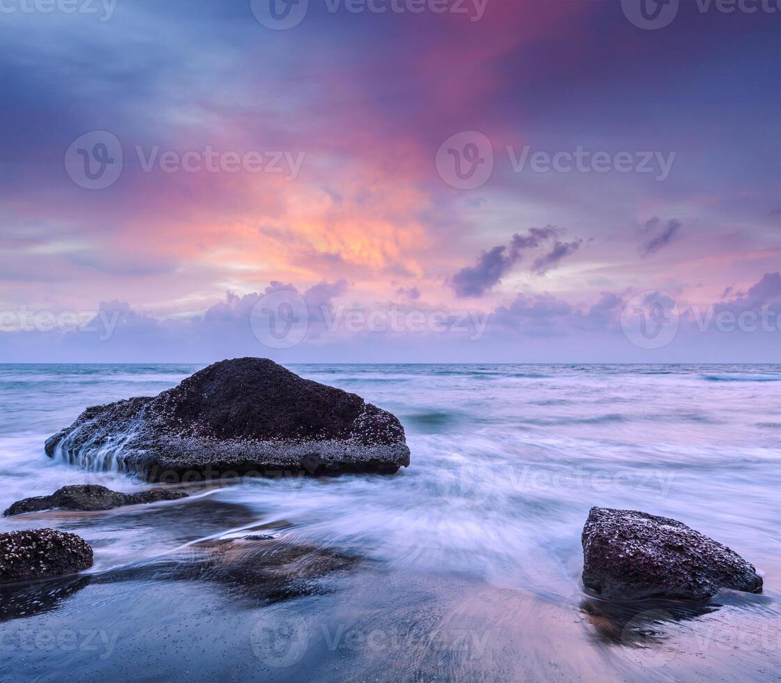 Waves and rocks on beach of sunset photo