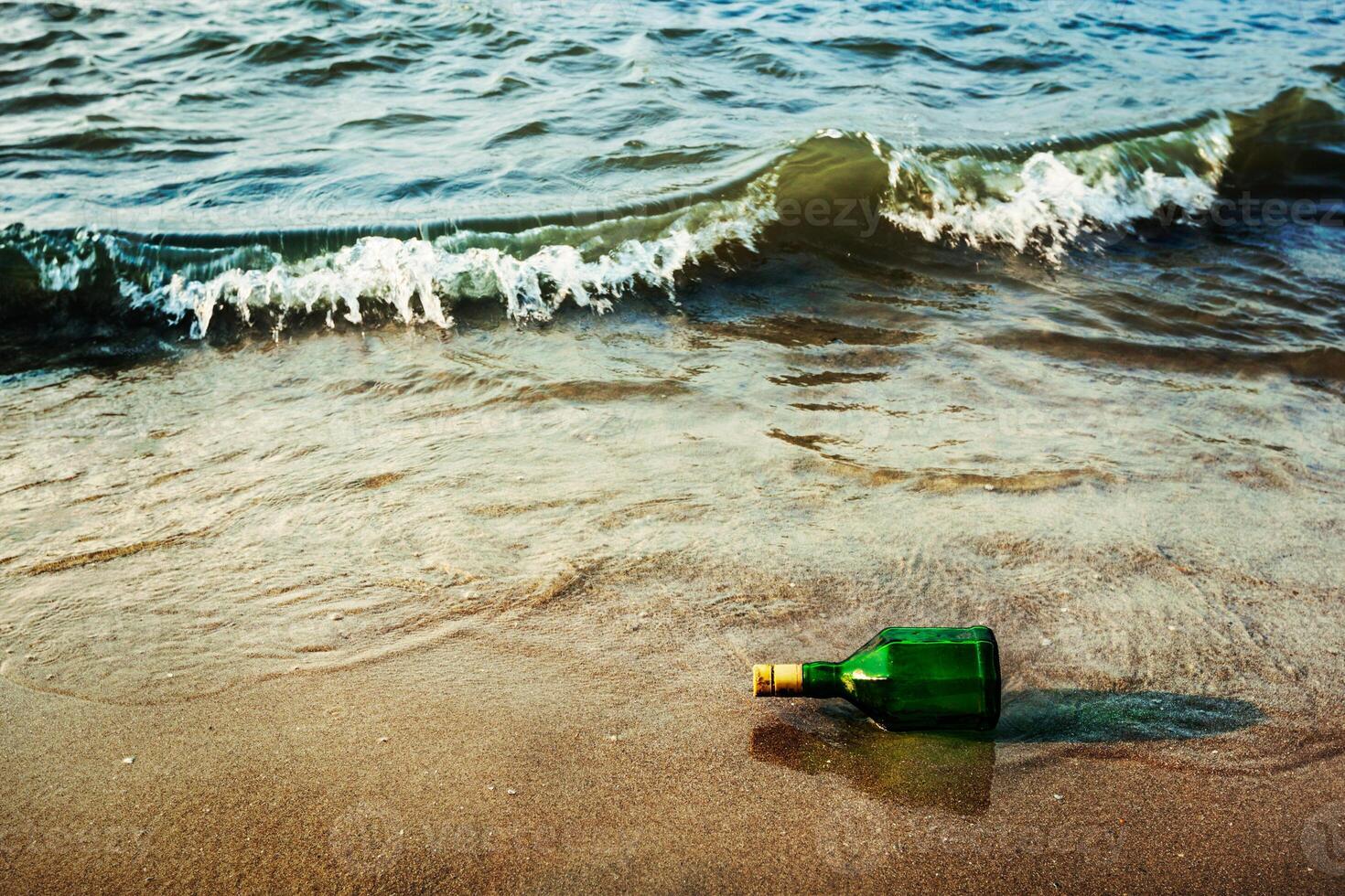 Message bottle on beach in waves photo