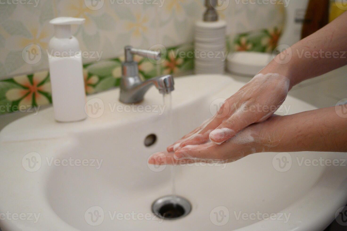 Cropped shot view of woman washing hands at sink basin faucet in toilet room. Washing your hands is one of the easiest ways to protect yourself and others from illnesses. photo