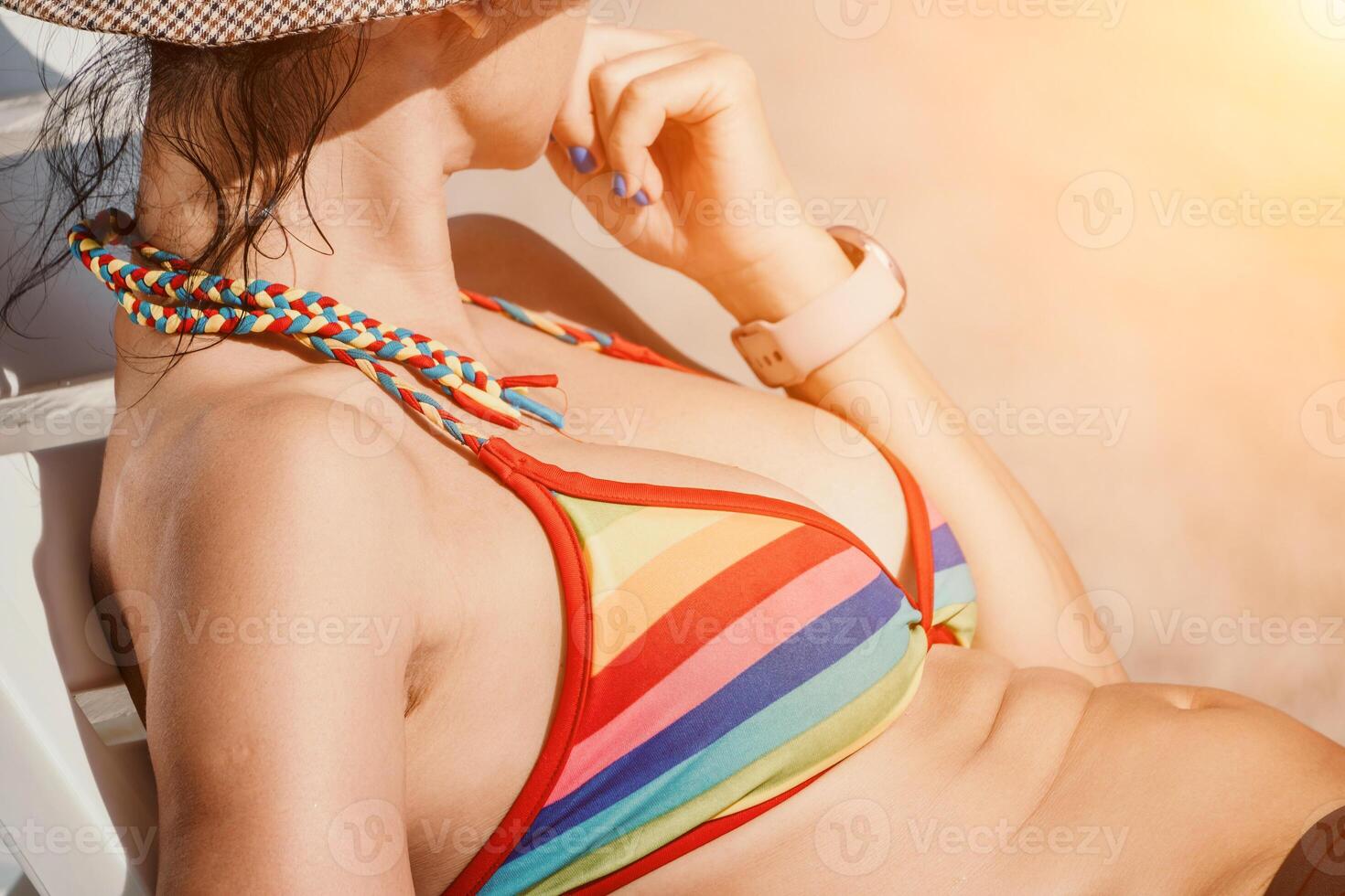 Woman in rainbow bikini. Happy tanned well looking middle aged woman in rainbow swimsuit at seaside, blue sea water in background. Holiday, vacation and recreational concept. photo