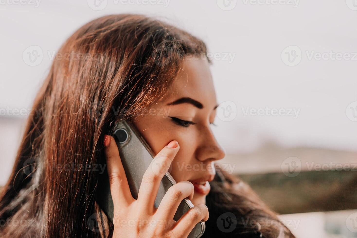 Happy young smiling woman with freckles outdoors portrait. Soft sunny colors. Outdoor close-up portrait of a young brunette woman and looking to the camera, posing against autumn nature background photo