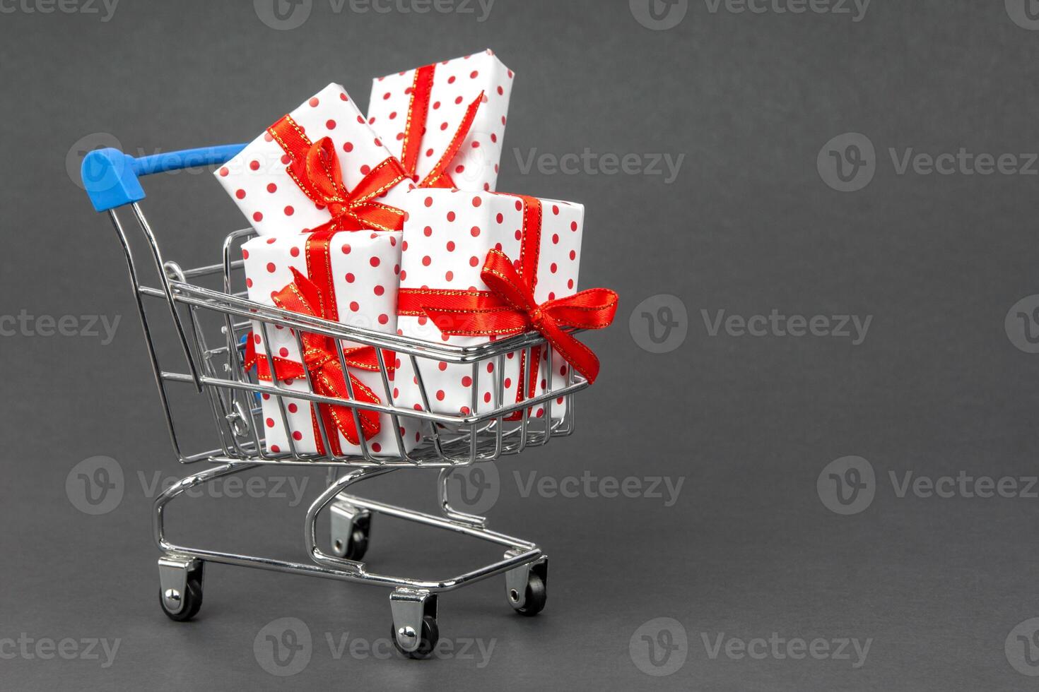 Grocery cart full of gifts on a dark gray background with place for copy space. Black Friday and holidays concept. photo
