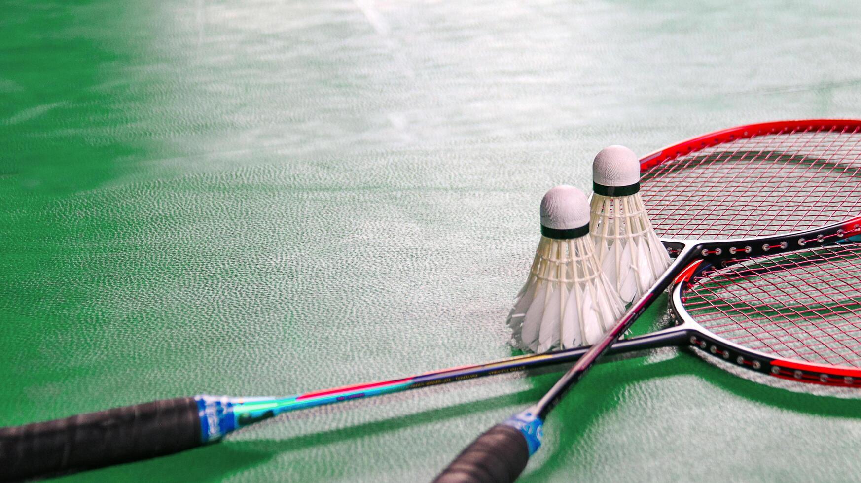 White badminton shuttlecocks and badminton rackets on green floor indoor badminton court photo