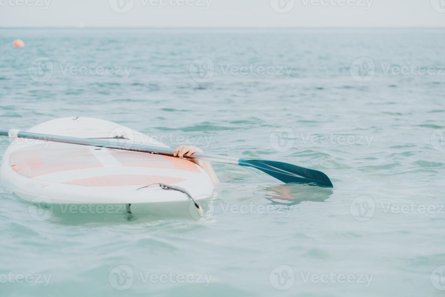 Sea woman sup. Silhouette of happy young woman in pink bikini, surfing on SUP board, confident paddling through water surface. Idyllic sunset. Active lifestyle at sea or river. photo