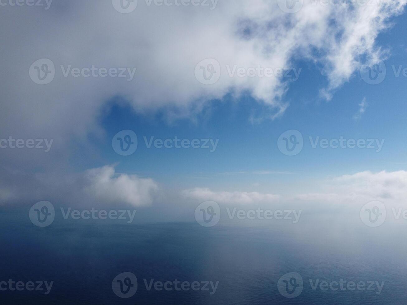 Aerial view. The drone flies over foggy and fluffy clouds. Blue sky sun and sea fog. Abstract aerial nature summer ocean sunset sea and sky background. Vacation, travel and holiday concept photo