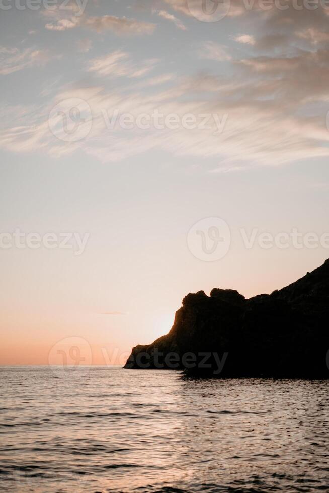 A red burning sunset over the sea with rocky volcanic cliff. Abstract nature summer or spring ocean sea background. photo