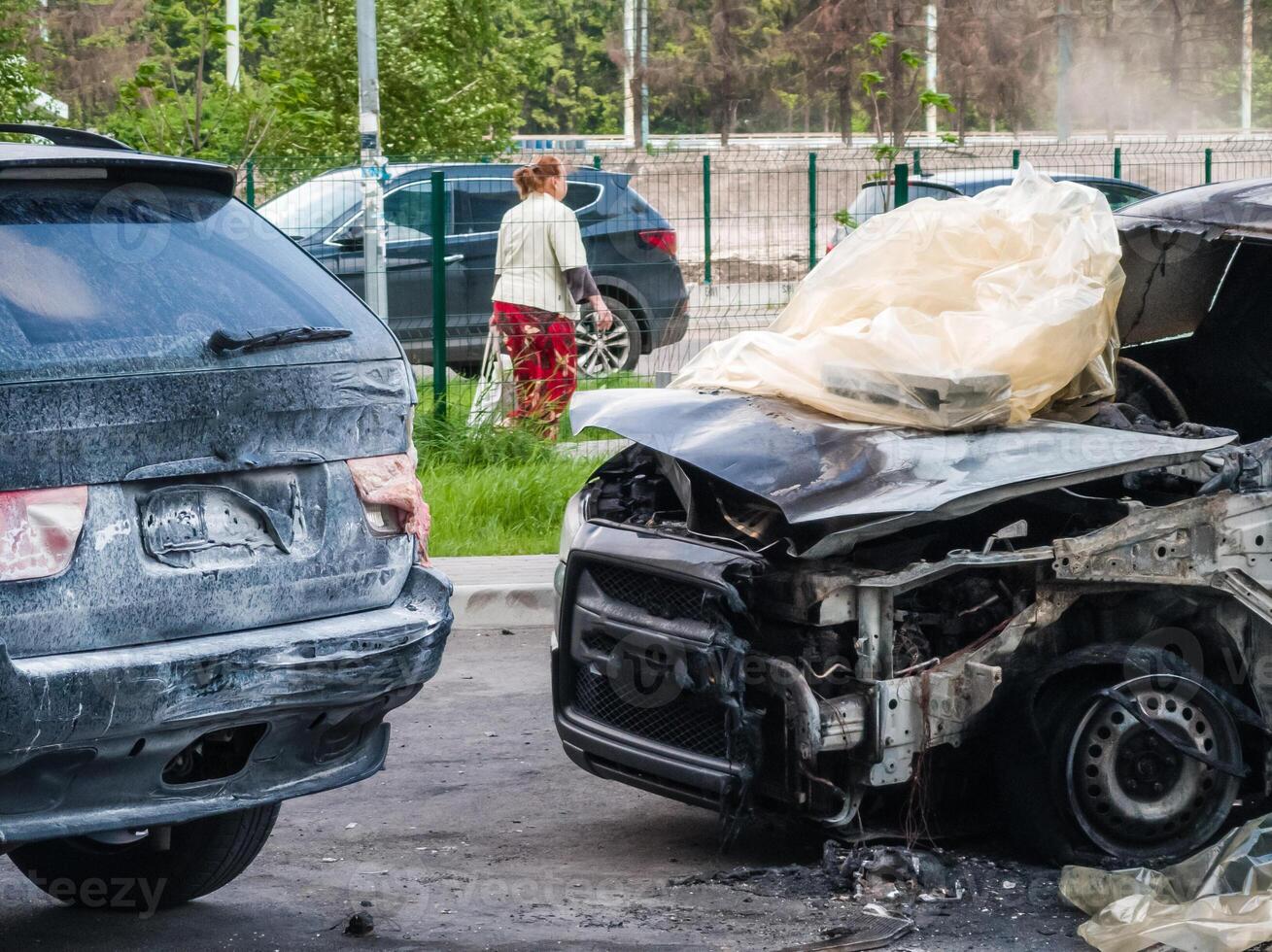 Broken and burned cars in the parking lot, accident or deliberate vandalism. Burnt car. Consequences of a car accident. Damaged by arson. Dump of civilian vehicles shot by Russian troops in Ukraine. photo