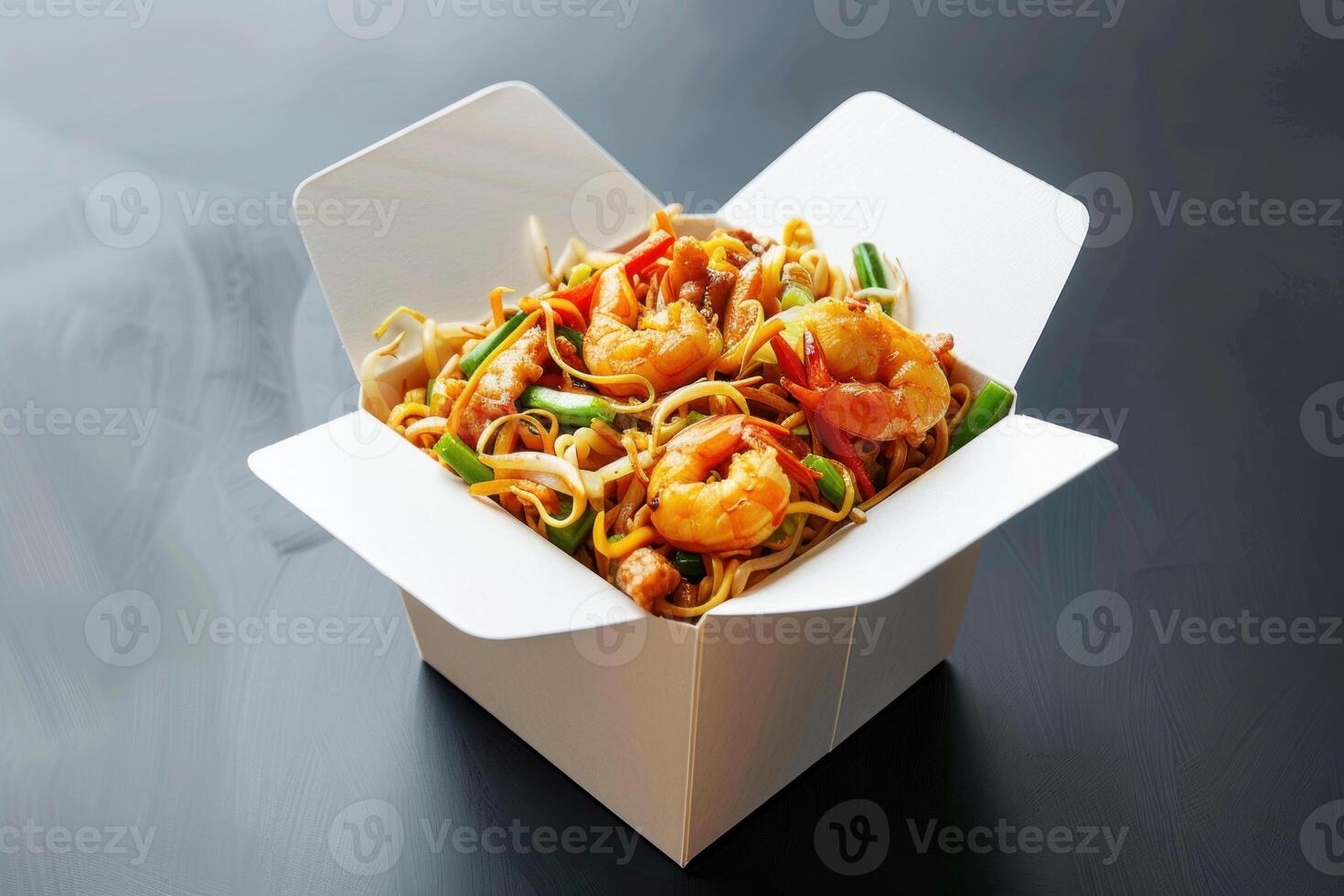 Wok with shrimps and vegetables in a takeaway box on dark background photo