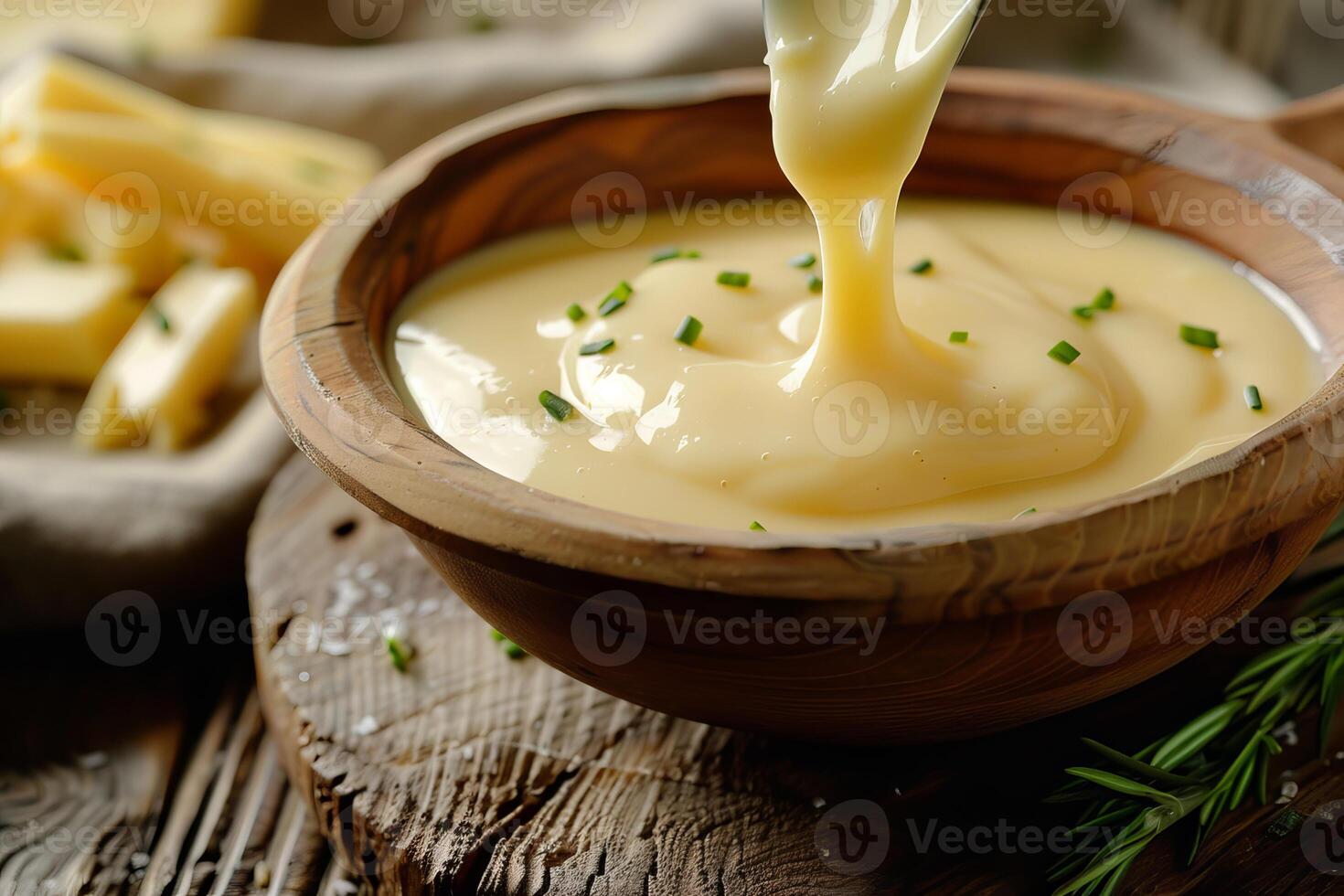 Melted cheese fondue being poured into a wooden bowl photo