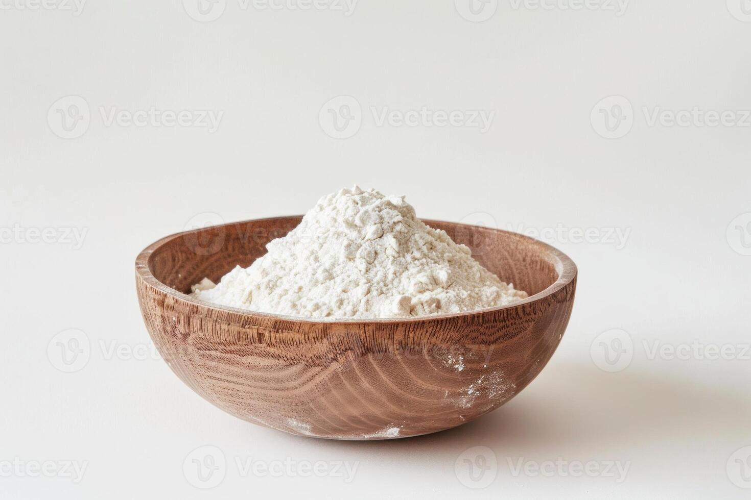 Wooden bowl overflowing with white flour on white background photo
