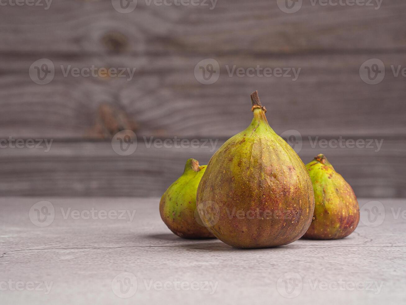 Ripe figs fruit are on a cement floor with a wooden wall background. High Vitamins fruit. Space for text. Healthy fruits and healthcare concept photo