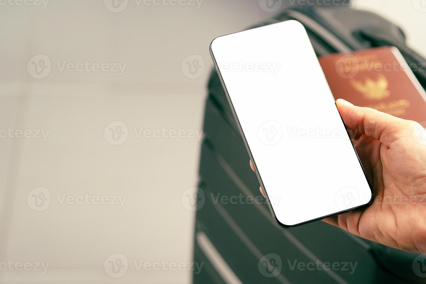 Hand holding of a smartphone with suitcase background. Close-up photo. Space for text. Technology and communication concept photo
