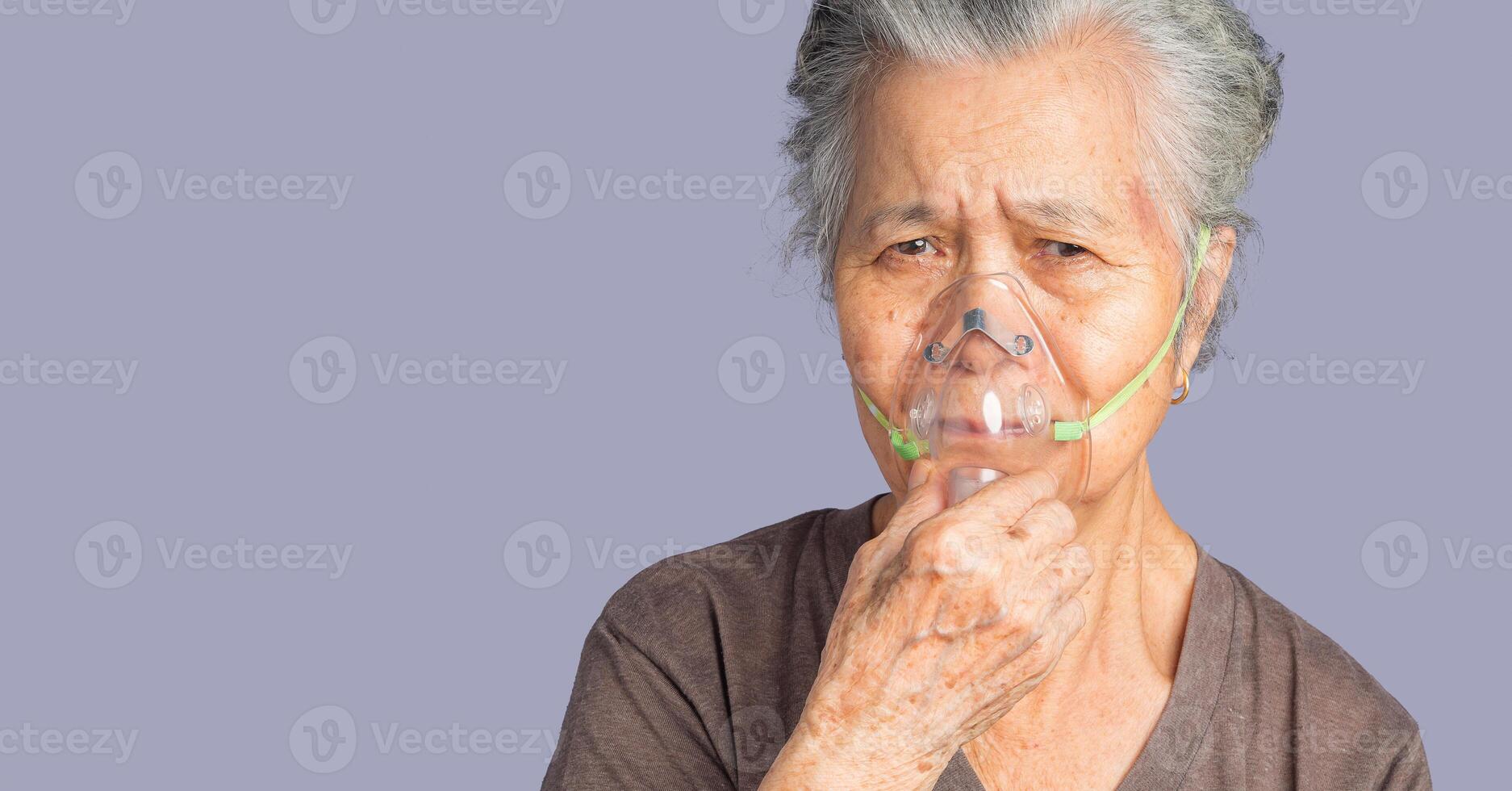 Portrait of an elderly Asian woman wearing a medical breathing mask. Sick senior woman wearing an oxygen mask inhalation, pneumonia coronavirus pandemic and undergoing treatment photo