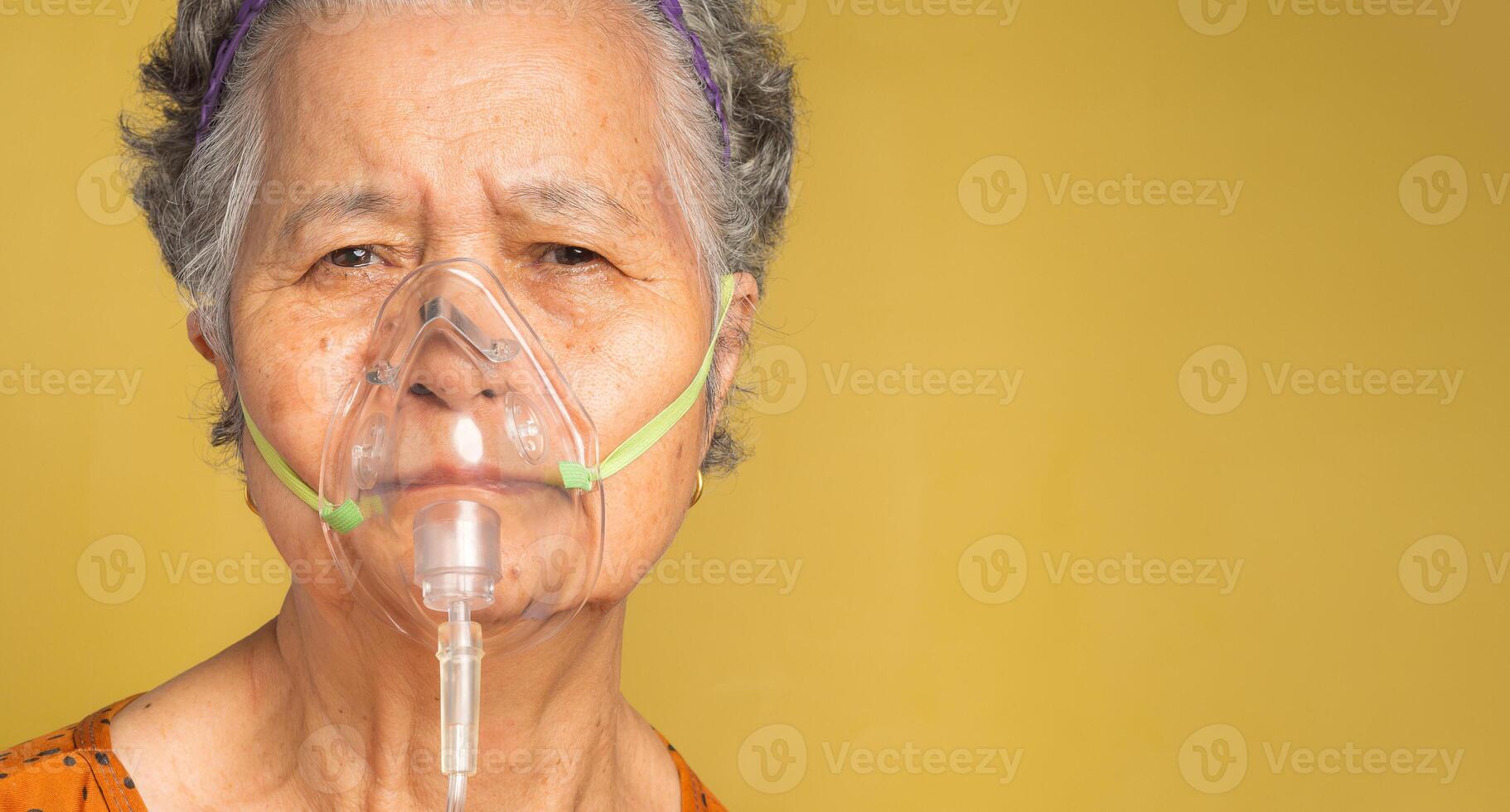 Close-up of a senior woman wearing a medical breathing mask. Sick senior woman wearing an oxygen mask inhalation, pneumonia coronavirus pandemic and undergoing treatment. Space for text photo