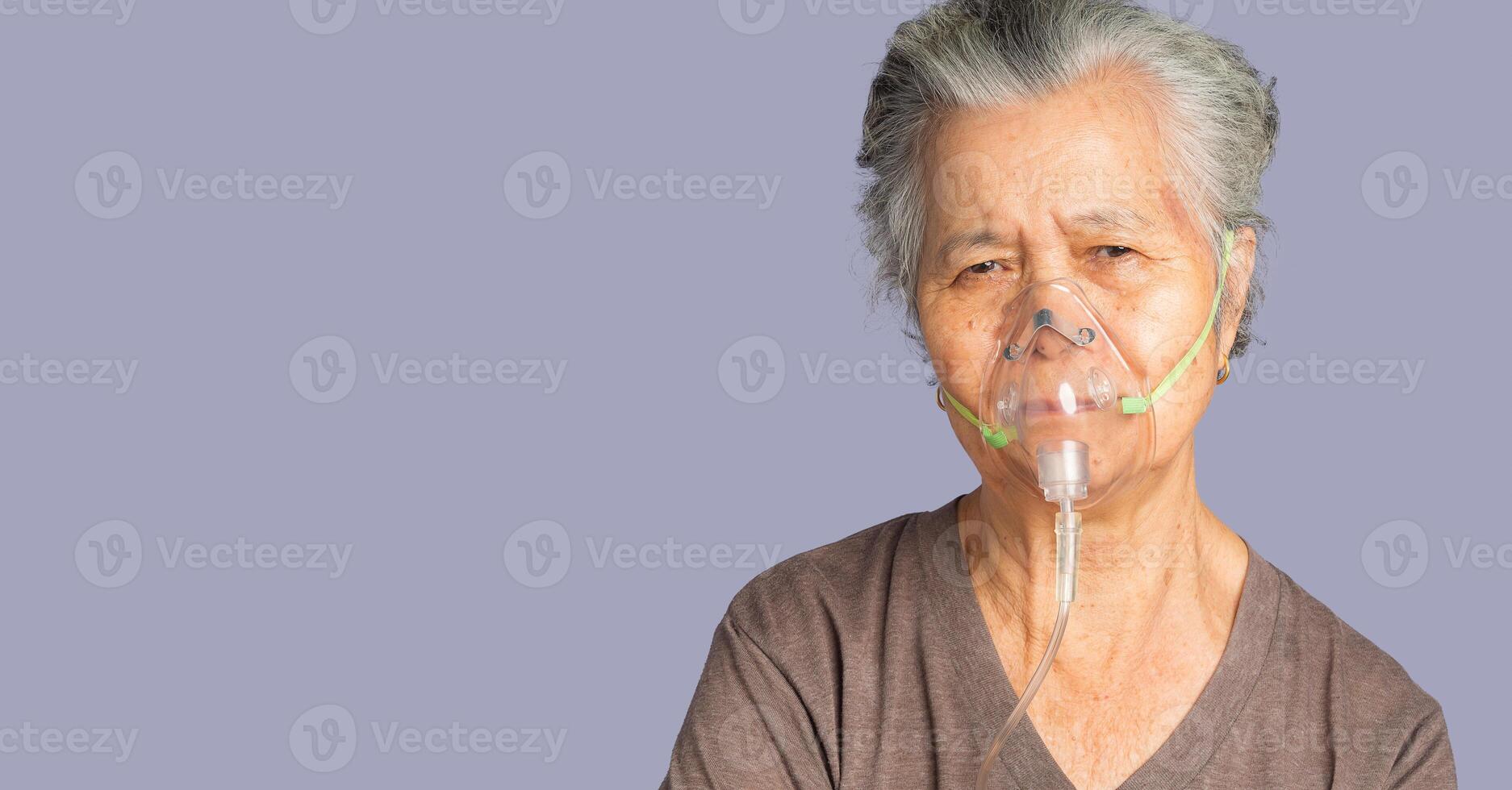 Close-up of an elderly Asian woman wearing a medical breathing mask. Sick senior woman wearing an oxygen mask inhalation, pneumonia coronavirus pandemic and undergoing treatment photo