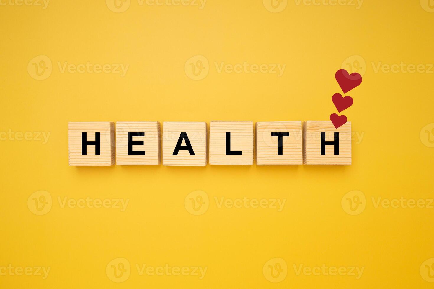 HEALTH word is written on wood blocks with three red heart symbols isolated on a yellow background. Top view. Close-up photo. Health and healthcare concept photo