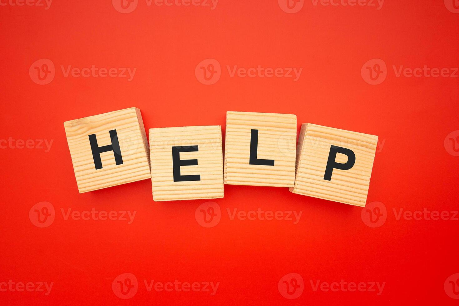 HELP word is written on wood blocks isolated on a red background. Top view. Close-up photo