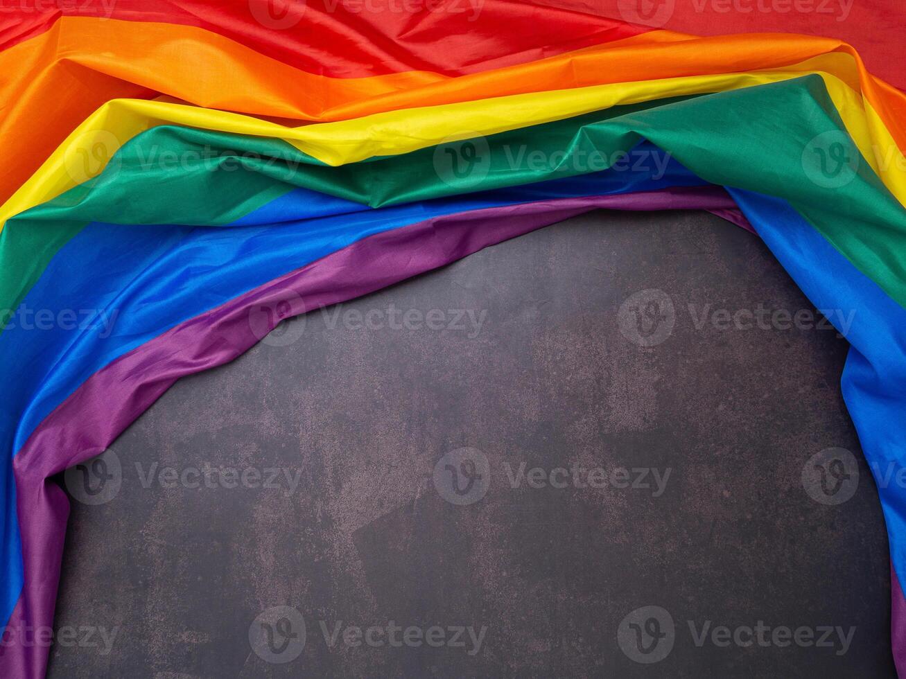 The rainbow flag is on a cement floor with space for text. photo