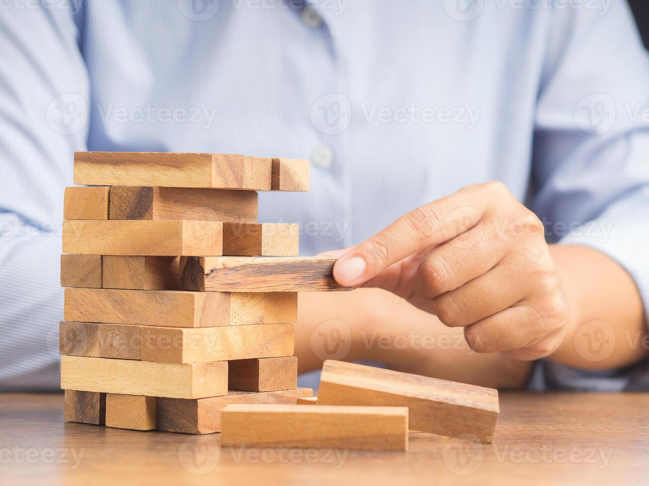 Close-up hand of the businessman playing wooden block game while sitting at the work table. Concept Risk of management and strategy plans for business growth and success photo