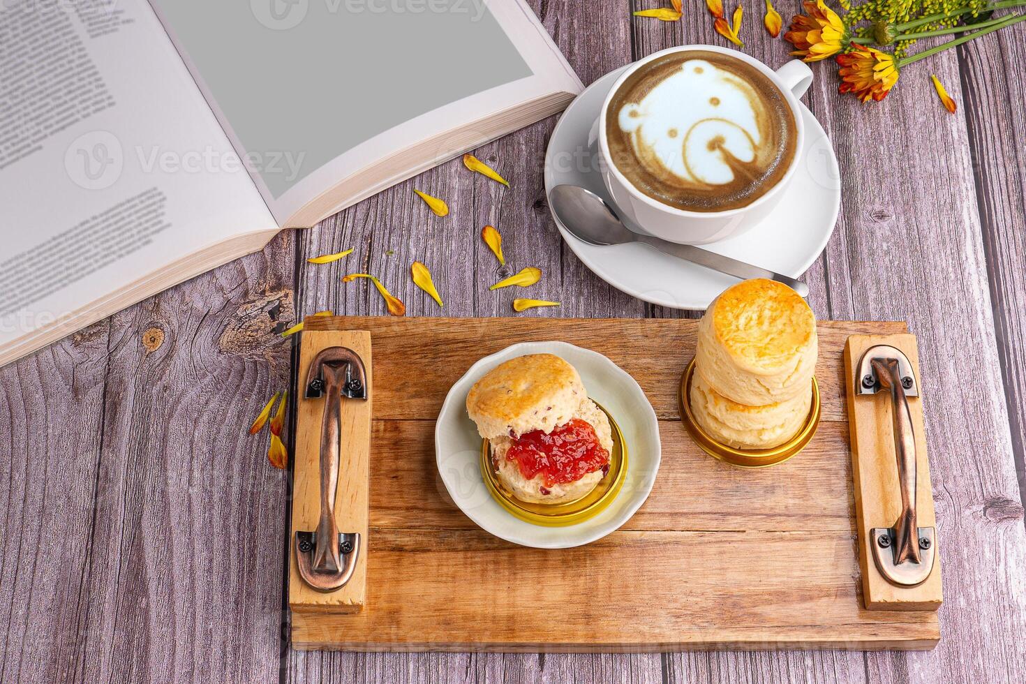 Scones traditional English delicious freshly baked homemade with strawberry jam served on a wooden tray with a coffee cup and a book on a wooden table. Top view. Relaxation concept photo