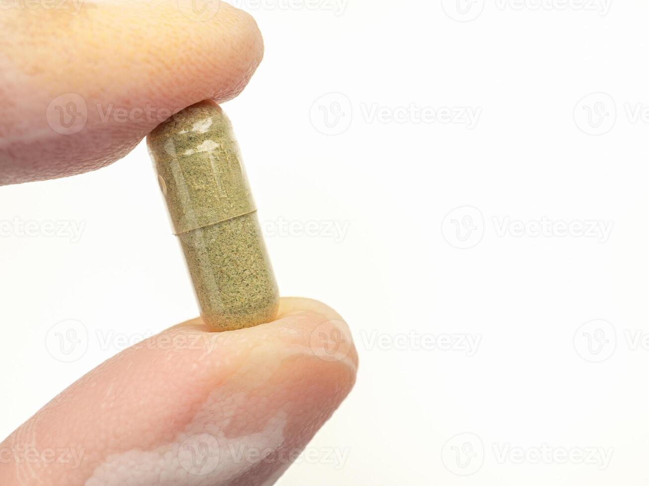 Hand holding of Andrographis paniculata capsule isolated on white background. Herbal, medicine, and healthcare concept photo