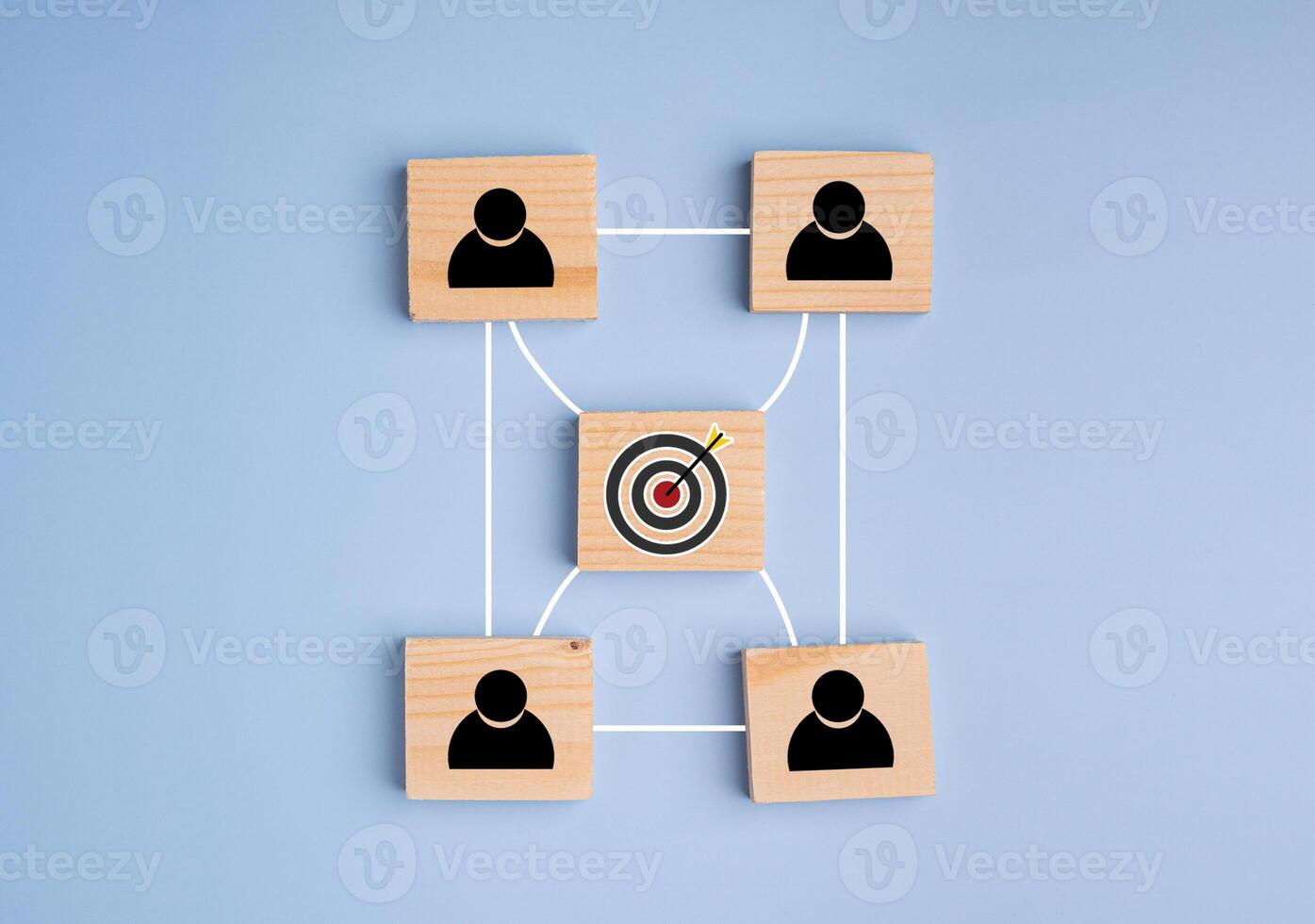 Top view of wooden blocks with black human icons and goal icon laid on a light blue background, Space for text. Flat lay. Teamwork and unity concept photo
