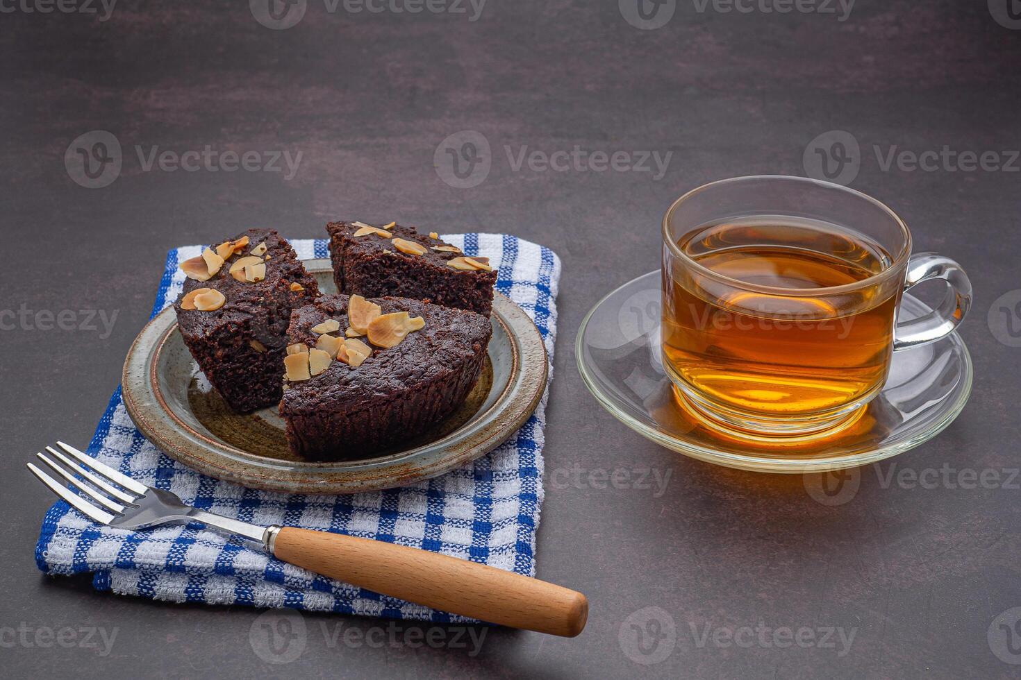 Pieces of fresh brownies on a plate with a teacup. Side view. Delicious chocolate pie. Dessert and relaxation concept photo