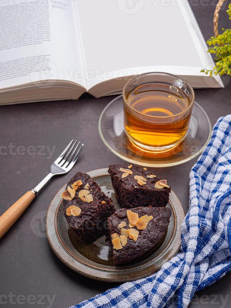 Brownies on a plate with a book and teacup. Side view. Delicious chocolate pie. Dessert and relaxation concept photo