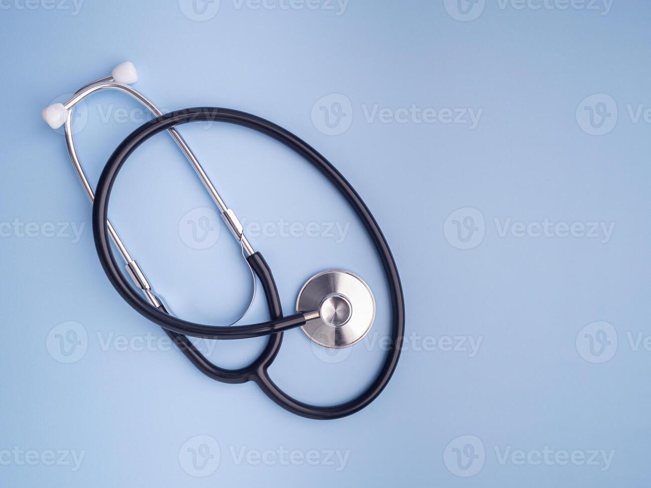 A stethoscope laid isolated on a light blue background. Close-up photo. Top view. Flat lay. Space for text. Healthcare and medicine concept photo