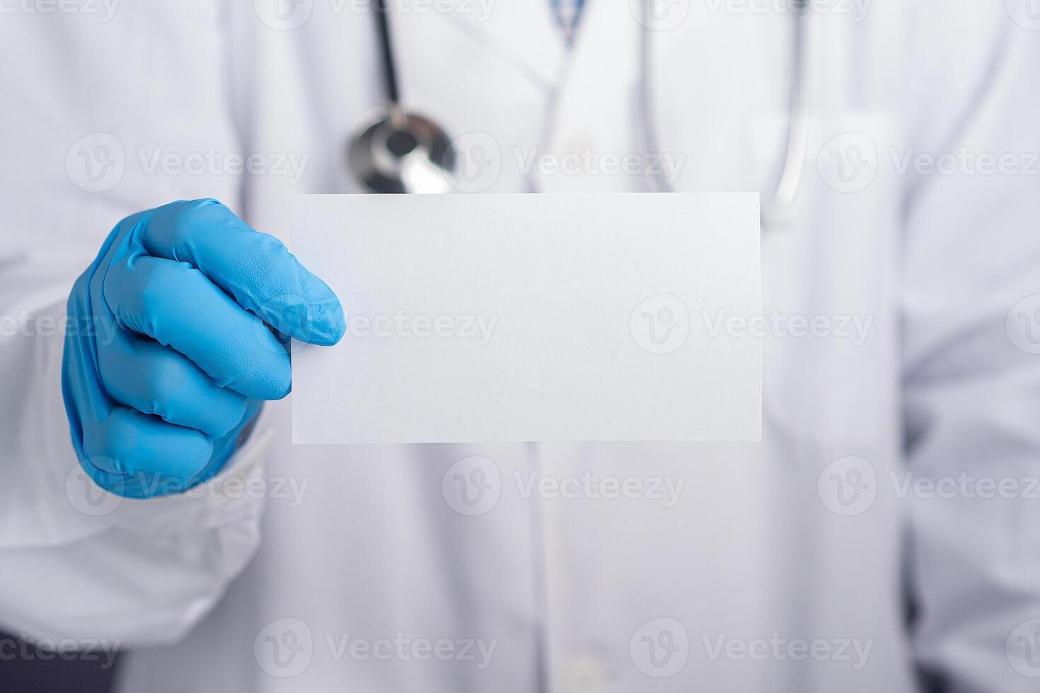 Hand of a doctor wearing protective gloves holding a white paper while standing in the hospital. Space for text. Medical and communication concept photo