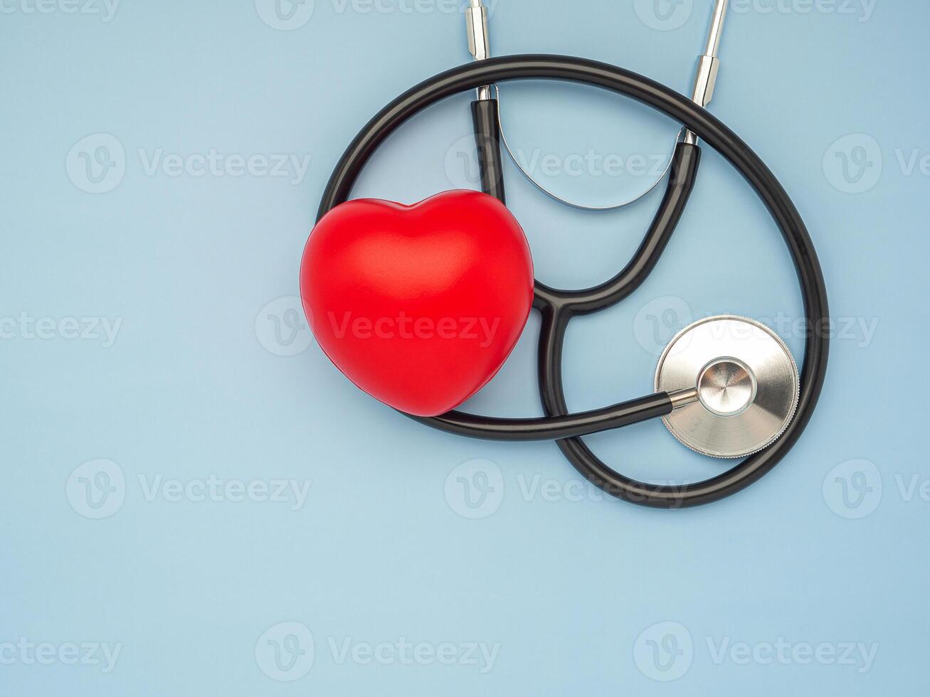 A stethoscope and red heart laid on a light blue background. Close-up photo. Top view. Flat lay. Space for text. Healthcare and medicine concept photo