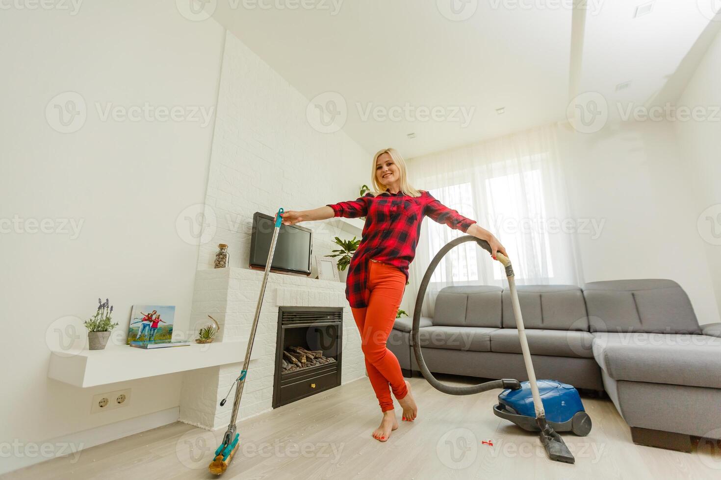 Young woman having fun while vacuuming at home. photo