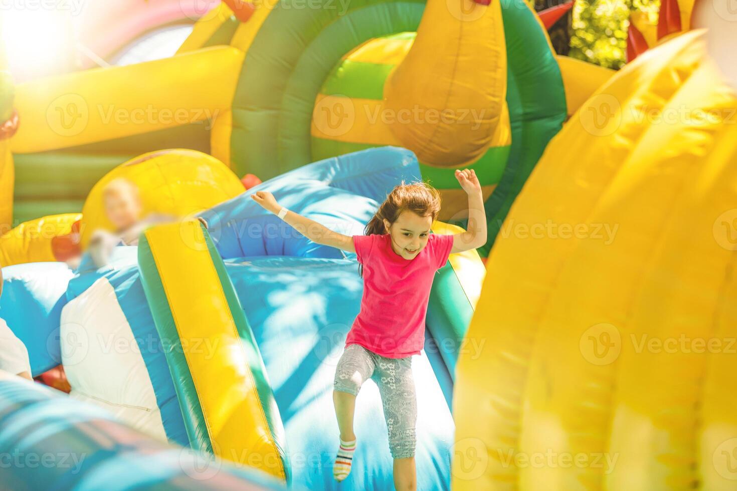 Happy little girl having lots of fun on a jumping castle during sliding. photo