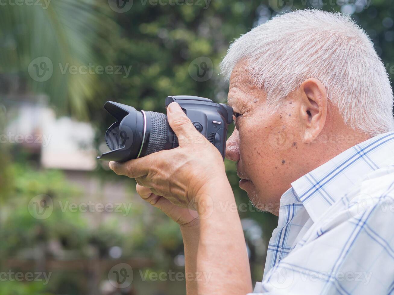 Senior man taking photographs with a digital camera while standing outdoors. Aged people photographer and relaxation concept photo